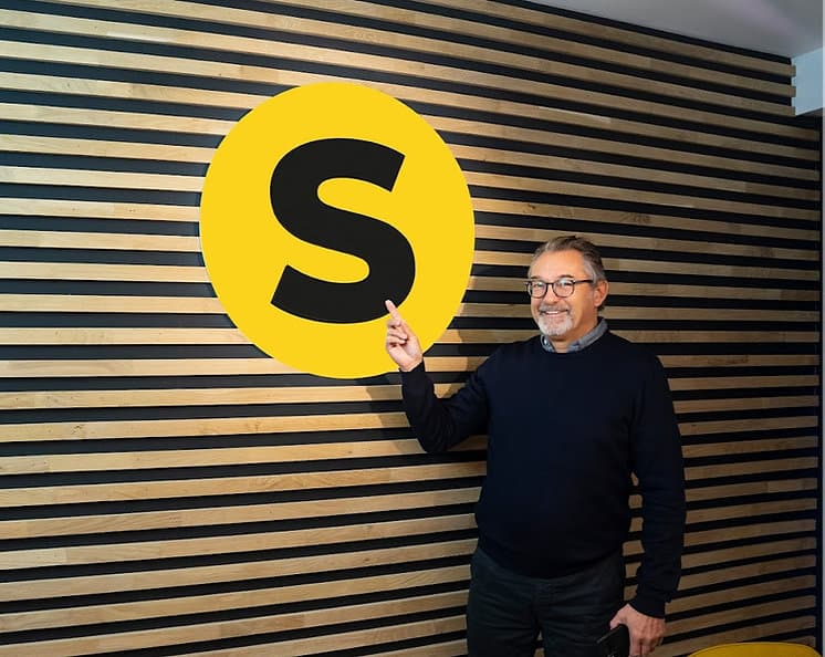 Patrick bij De Steenboer wijst naar het S-logo op kantoor